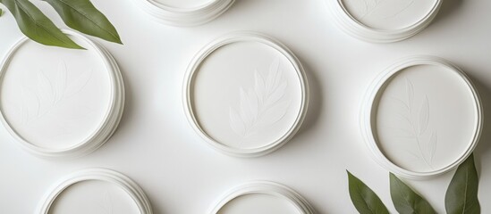Poster - White round lids with leaf motifs arranged on a surface, providing blank space for branding or product text in a natural setting.