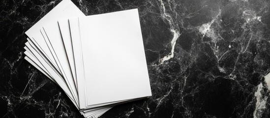 Poster - Blank white sheets on a polished black marble surface creating a modern backdrop for showcasing professional designs or text elements.