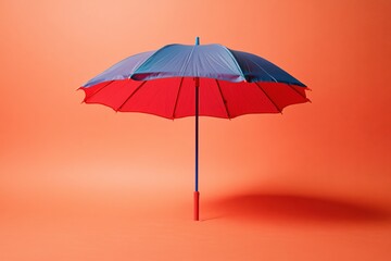 Poster - Vibrant umbrella with blue and red panels on a solid orange background studio shot