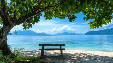 Poster - Serene beach view featuring a bench under a tree with a calm sea and mountains in the background ideal for tranquil imagery or text overlay
