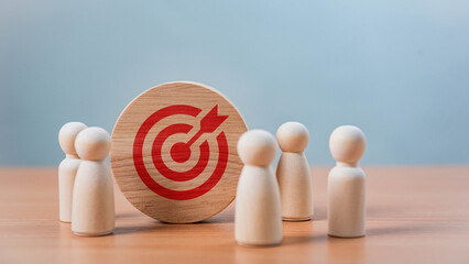 Poster - Teamwork and Business Goals Execution. A wooden disc with a bullseye and arrow icon is placed among wooden figures, symbolizing goal setting, business strategy, leadership, and teamwork.