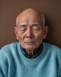 © sevenSkies - Elderly Asian man sleepy bald head light blue sweater on brown background