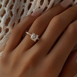 © CreativeInside - A macro shot photograph of a blue cushion cut moissanite with three round stones on the sides worn on a hand. Sterling silver material. Extreme sparkle and light refraction.