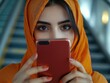 © Elena - Contemplative Orange Hijab Woman with Phone