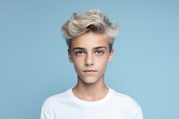 Wall Mural - A young man with blonde hair and blue eyes is standing in front of a blue wall