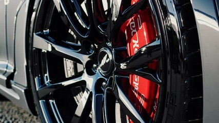 Aufkleber - A tight focus on a glossy black alloy wheel, with a striking red brake caliper visible through the spokes, captured in a well-lit studio setting.