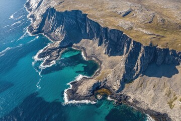 Poster - Aerial view of a rocky coastline with blue water, suitable for use in travel or landscape photography