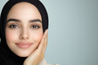 © aciddreamStudio - Young Arabic woman with peaceful smile and hand on cheek against light gray background for cosmetics ad concept