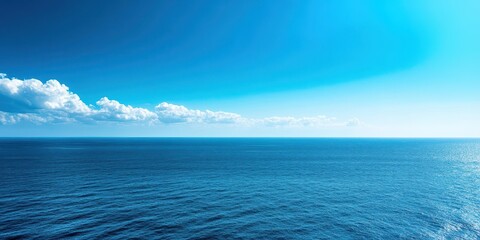 Wall Mural - A tranquil view of the vast ocean under a clear blue sky with soft clouds.