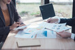 © Kritdanai - Financial Collaboration: A close-up shot of a business meeting where two professionals carefully examine financial documents and data. They are surrounded by a table full of reports and charts.
