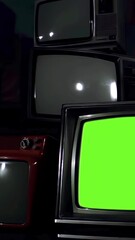 Wall Mural - old tv turns on with green screen amidst many powered-off vintage tvs - dolly shot - vertical 4k