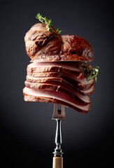 Wall Mural - Sliced smoked gammon with thyme branches on a fork.