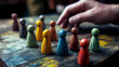© graphic_titan - A hand reaching out towards a row of colorful wooden game pieces on a vintage wooden surface, a powerful image about choices and leadership.