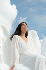 Wall Mural - A woman in a white dress is sitting on a cloud. She is smiling and she is at peace