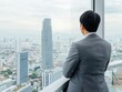 © Sergey - A businessman in a suit stands in a high-rise, gazing at a sprawling urban skyline through a large window, exhibiting a serene and contemplative mood.