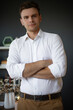 © My Ocean studio - A confident man in a white shirt with arms crossed, standing in a modern office with a minimalist background, showing a relaxed and thoughtful expression, perfect for business, leadership