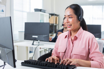 Confident Asian woman working on computer for online customer support, telemarketing assistance, giving advice online using headset at call center office. Asian businesswoman customer service at work.