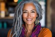 © Vertigo Images - Portrait of a smiling middle-aged woman with gray dreadlocks, wearing a colorful scarf.