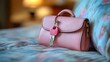 © Linus - A pink purse with a key on it is laying on a bed