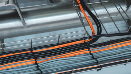 Aufkleber - A long metal pipe with many wires hanging out of it. The wires are black and orange. The wires are connected to a metal grid