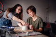 © Oleksii Yemelianov - Two women working together on a clay pottery project, focusing on shaping and detailing the piece. The scene highlights collaboration, creativity, and concentration.