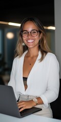 Wall Mural - A woman is sitting at a desk with a laptop in front of her. She is wearing glasses and a white shirt