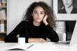 © Kubista - Portrait of a Young Woman with Curly Hair Sitting at a Desk in a