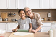 © fizkes - Funny cuisine. Happy joyful mature granny preteen age girl grandchild posing for cute family portrait at house kitchen looking at camera with noses in flour enjoy cooking dough baking pastry for lunch