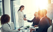 © peopleimages.com - Handshake, contract and deal with business people in meeting for merger success, acquisition and thank you. Teamwork, loan agreement and banking firm with employees in office with lens flare