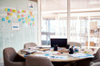 © peopleimages.com - Office, creative company and documents on desk for plan, design and advertising in workplace. Empty boardroom, interior background and paperwork, sticky notes and laptop on table for startup business