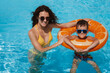 © alexkoral - happy young mother and child boy son in swimming pool at a hotel on vacation at a resort in the summer