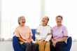 © artitwpd - Three senior women sit on a blue couch, laughing and enjoying joyful conversation. The bright indoor setting highlights friendship, happiness, and positive aging, capturing the beauty of companionship