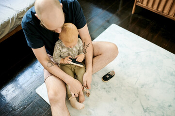 Sticker - Helping, shoes and father with baby in living room for ready, morning routine and clothes. Bonding, support and care with man and young child in family home for happy, change and learning from above