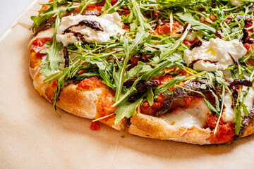 Wall Mural - A delicious pizza emerges from the oven, boasting vibrant toppings of arugula, sun-dried tomatoes, and creamy burrata. The rustic wooden table adds warmth to this culinary delight. 