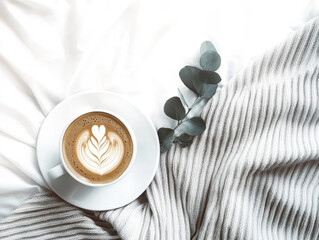 A cozy morning with a warm cappuccino and soft gray knitted blanket on a white bed