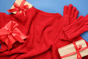 Poster - Stylish red sweater, gloves and gift boxes on blue background, closeup