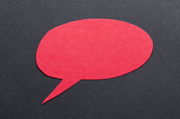 Poster - Red cut out blank paper speech bubble of round shape with copy space for text on dark background, flat lay top view conceptual backdrop