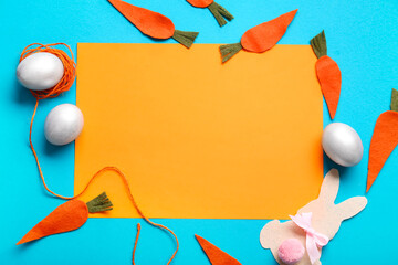 Wall Mural - Paper bunny, Easter eggs, carrots and blank card on blue background. Closeup