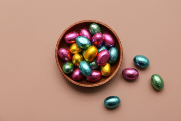 Wall Mural - Bowl of chocolate Easter eggs in foil on beige background