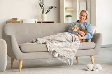 Wall Mural - Beautiful woman with plaid and cute cat lying on sofa at home