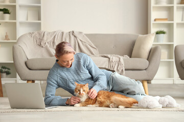 Wall Mural - Beautiful woman with cute cat and soft slippers on floor at home