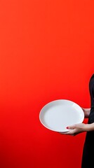 Fototapete - A person in a waiter is uniform, holding a plate, with a bright clean backdrop