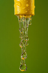 Poster - close-up of water droplets flowing from a yellow nozzle against a green background, symbolizing clea