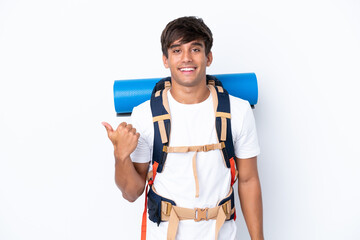 Wall Mural - Young mountaineer woman with a big backpack over isolated white background pointing to the side to present a product