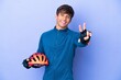 © luismolinero - Young cyclist caucasian man isolated on purple background smiling and showing victory sign