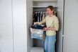 © AnastasiiaAkh - Woman arranging old unwanted clothes into a plastic container to sell in thrift store