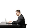 © peshkova - Businessman in formal suit typing on laptop at desk, isolated on white background. Professional work concept, clean minimalist layout