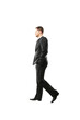 © peshkova - Man wearing a formalsuit walking side view with hands in pockets on white background. Professional, business concept, isolated style