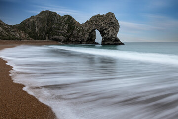 Wall Mural - Beautiful atmospheric landscape image of rock arch and cliffs on Jurassic Coast in England during Winter sunset