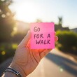 © venis - A hand holding a sticky note with ‘Go for a Walk’, healthy lifestyle encouragement